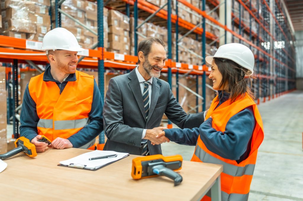 Manager shaking hands with worker in logistics warehouse